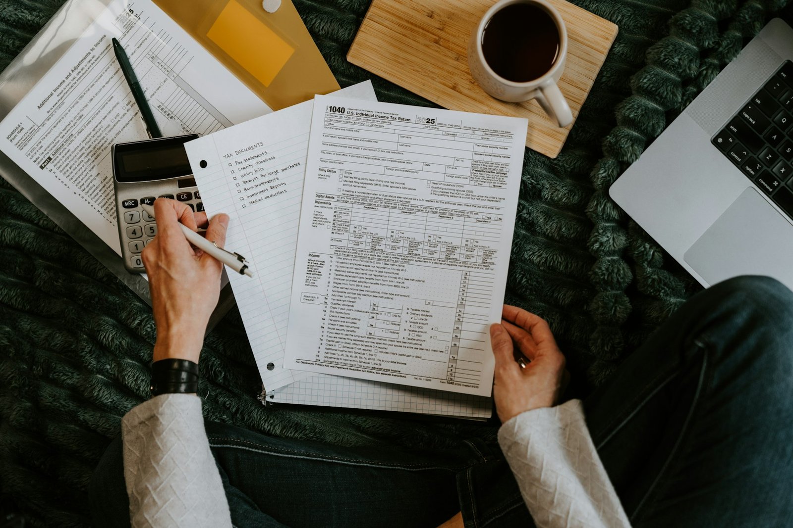 Person reviewing documents with calculator and laptop